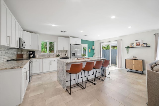 kitchen featuring a kitchen island, white cabinetry, stainless steel appliances, and a wealth of natural light