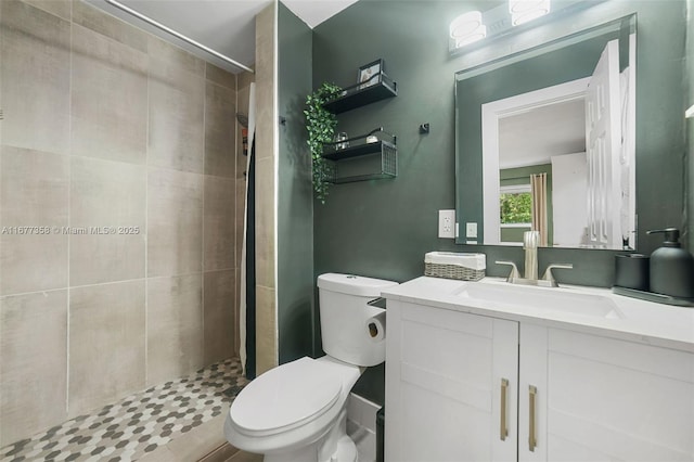 bathroom featuring vanity, toilet, and a tile shower