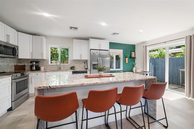 kitchen with white cabinetry, stainless steel appliances, and a kitchen island