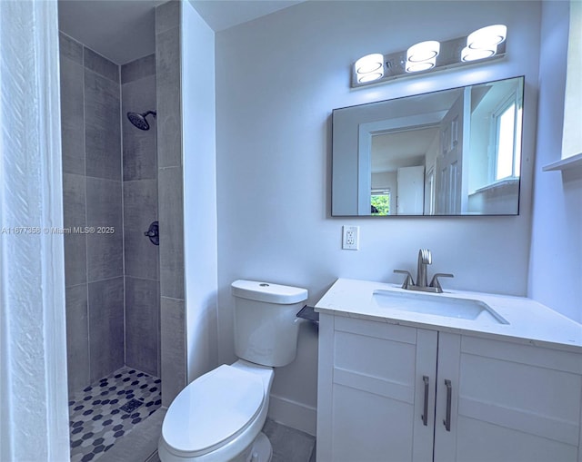 bathroom featuring vanity, toilet, a wealth of natural light, and a tile shower