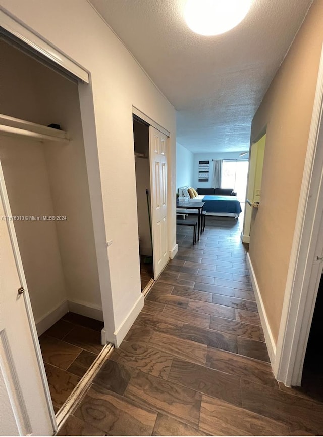 hallway featuring a textured ceiling and dark hardwood / wood-style floors