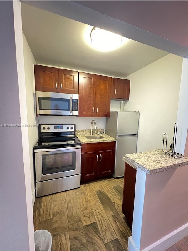 kitchen featuring light hardwood / wood-style floors, stainless steel appliances, sink, and kitchen peninsula