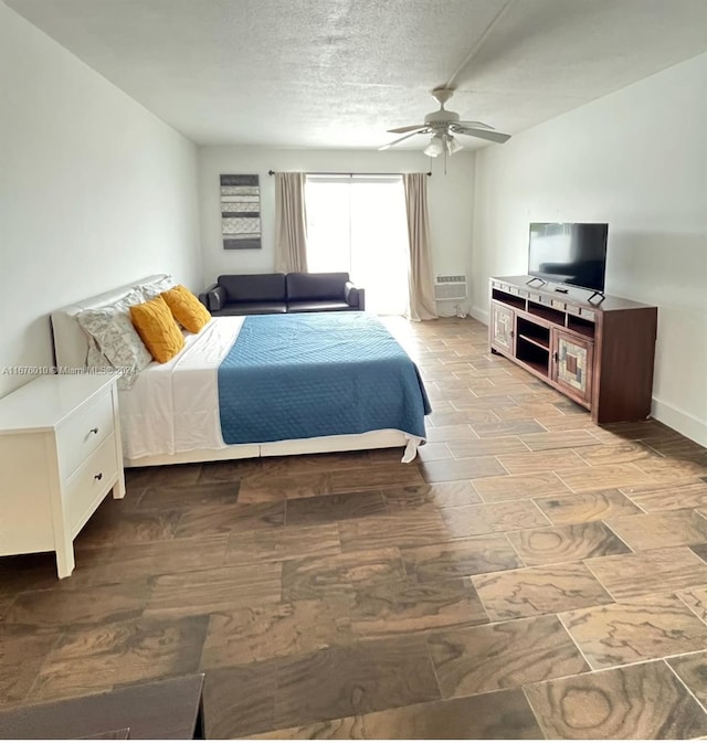 bedroom with ceiling fan, a textured ceiling, light wood-type flooring, and a wall mounted air conditioner