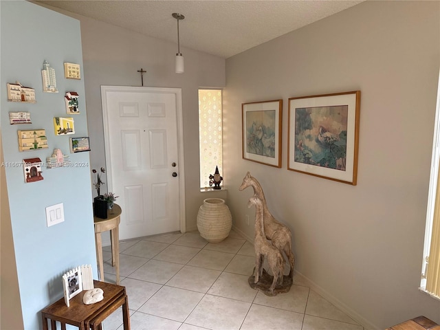 foyer featuring lofted ceiling, a textured ceiling, and light tile patterned floors