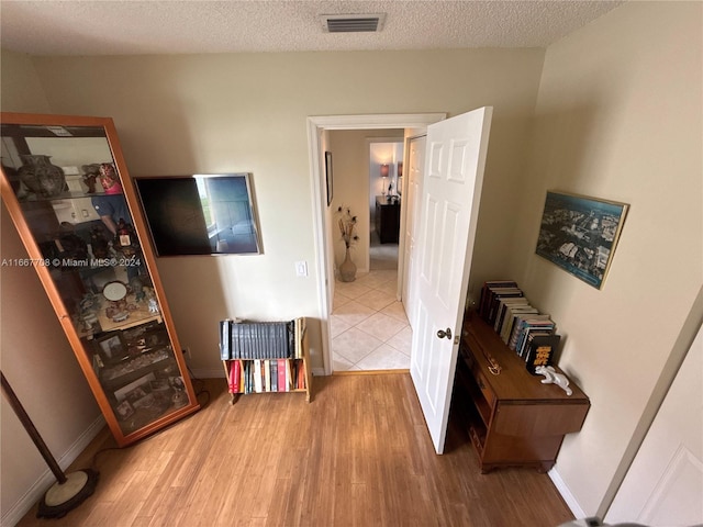 hallway with a textured ceiling and hardwood / wood-style flooring