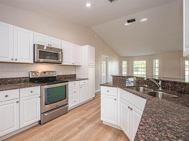 kitchen featuring appliances with stainless steel finishes, sink, light hardwood / wood-style floors, lofted ceiling, and white cabinets