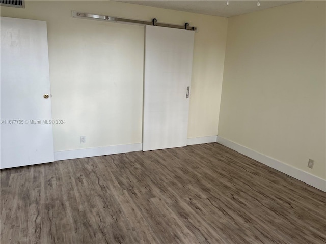 empty room featuring a barn door and hardwood / wood-style flooring