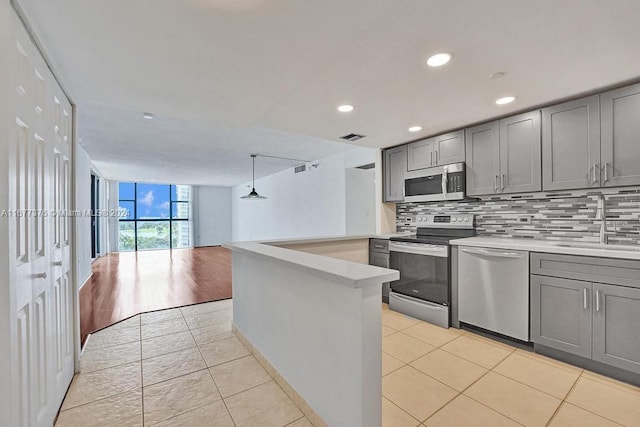 kitchen featuring tasteful backsplash, appliances with stainless steel finishes, pendant lighting, gray cabinetry, and sink