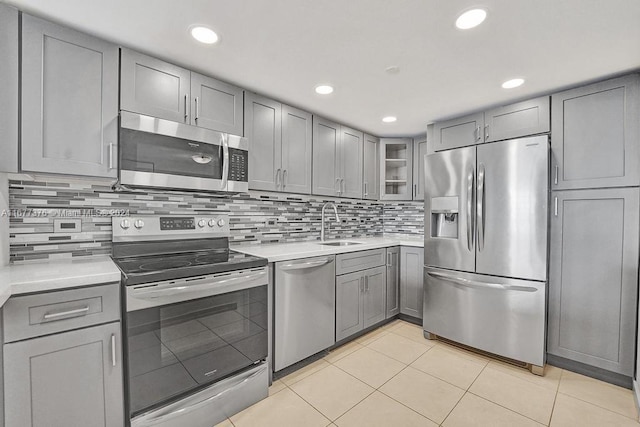 kitchen featuring gray cabinetry, backsplash, stainless steel appliances, and light tile patterned flooring