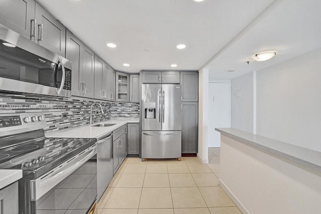 kitchen featuring tasteful backsplash, light tile patterned floors, sink, gray cabinets, and stainless steel appliances