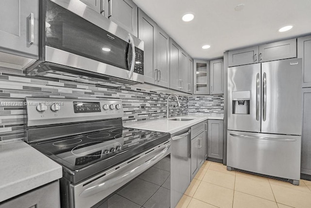 kitchen featuring decorative backsplash, gray cabinetry, stainless steel appliances, sink, and light tile patterned floors