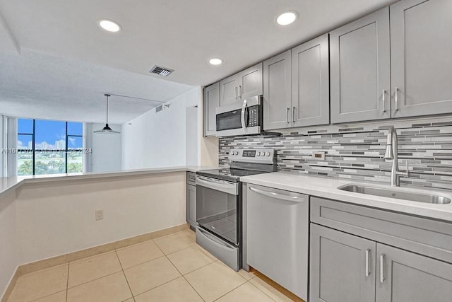 kitchen featuring appliances with stainless steel finishes, sink, backsplash, pendant lighting, and gray cabinets