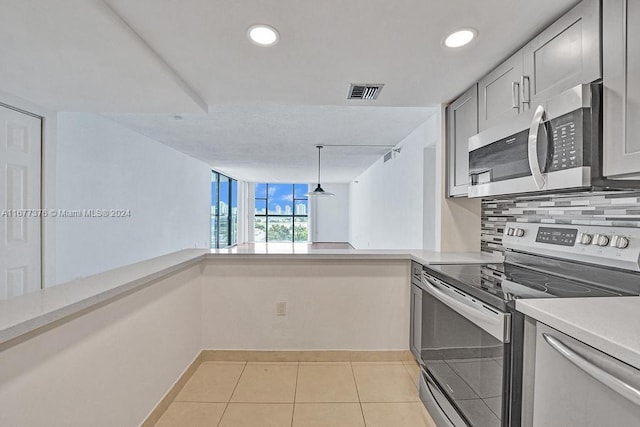 kitchen with hanging light fixtures, stainless steel appliances, gray cabinets, decorative backsplash, and light tile patterned floors