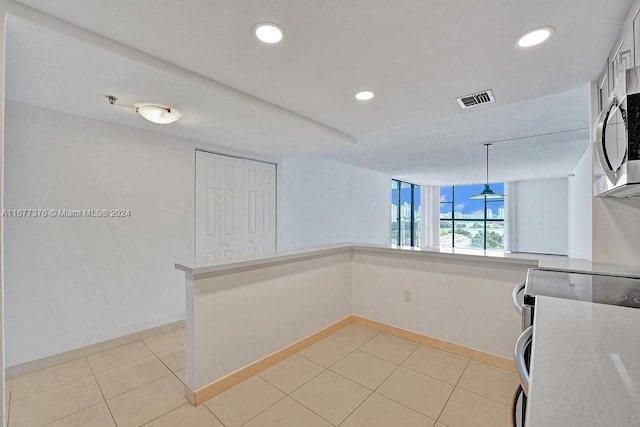 kitchen with kitchen peninsula, white cabinets, hanging light fixtures, light tile patterned floors, and stainless steel appliances