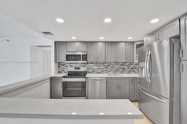 kitchen with gray cabinetry, tasteful backsplash, appliances with stainless steel finishes, and sink