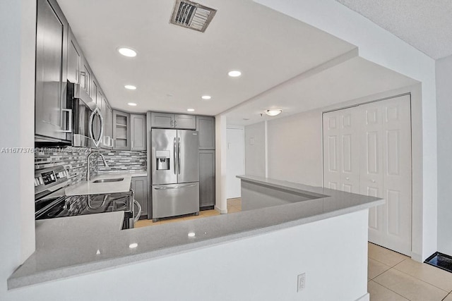 kitchen featuring sink, stainless steel appliances, light tile patterned flooring, and kitchen peninsula