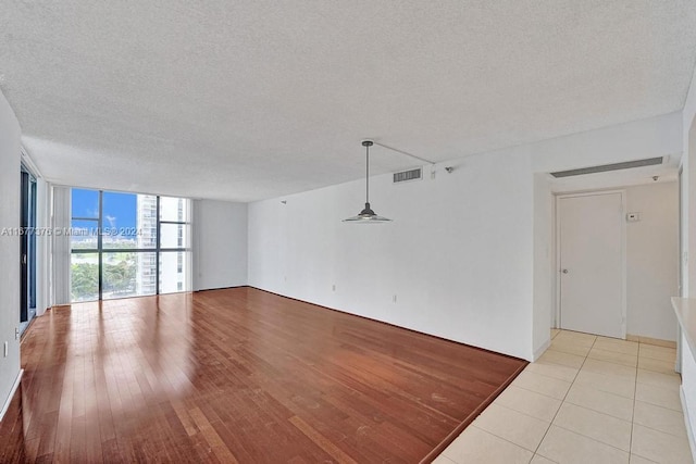 unfurnished living room featuring expansive windows, light hardwood / wood-style flooring, and a textured ceiling