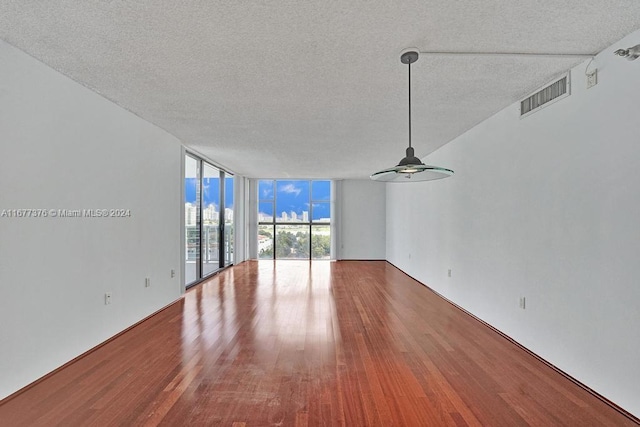 empty room featuring hardwood / wood-style floors, ceiling fan, a textured ceiling, and floor to ceiling windows