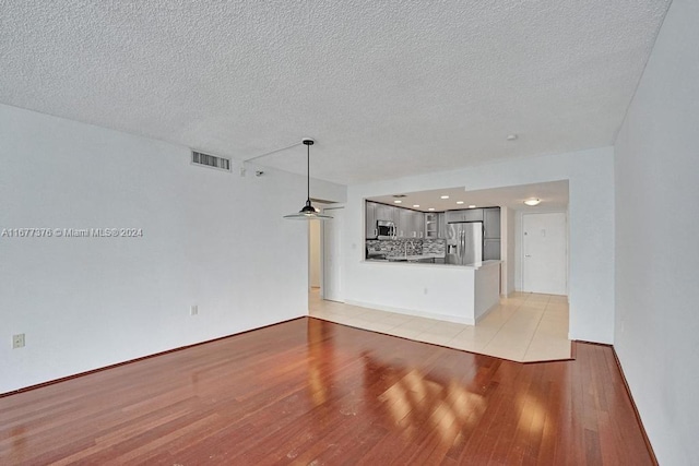 unfurnished living room with light hardwood / wood-style floors and a textured ceiling