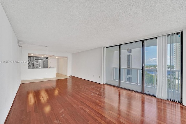 unfurnished living room featuring a textured ceiling, wood-type flooring, and floor to ceiling windows