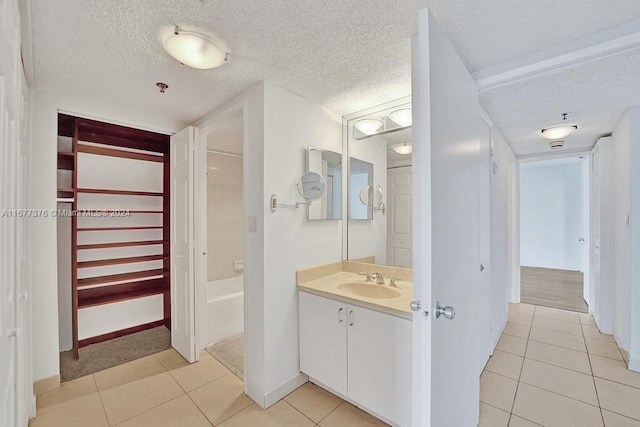 bathroom featuring vanity, a textured ceiling, tile patterned floors, and a bathtub