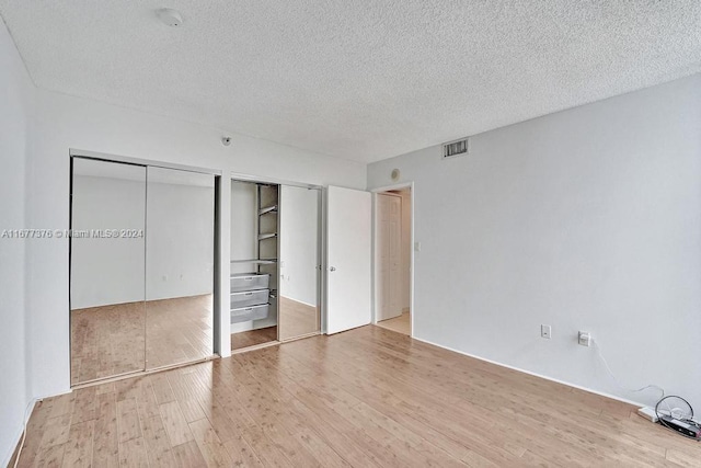 unfurnished bedroom with multiple closets, hardwood / wood-style flooring, and a textured ceiling