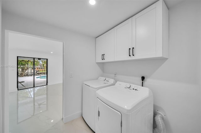 clothes washing area featuring cabinets and separate washer and dryer