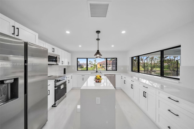 kitchen featuring a healthy amount of sunlight, a kitchen island, white cabinetry, and appliances with stainless steel finishes