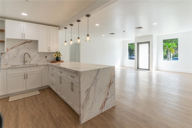 kitchen with kitchen peninsula, white cabinetry, sink, and light wood-type flooring