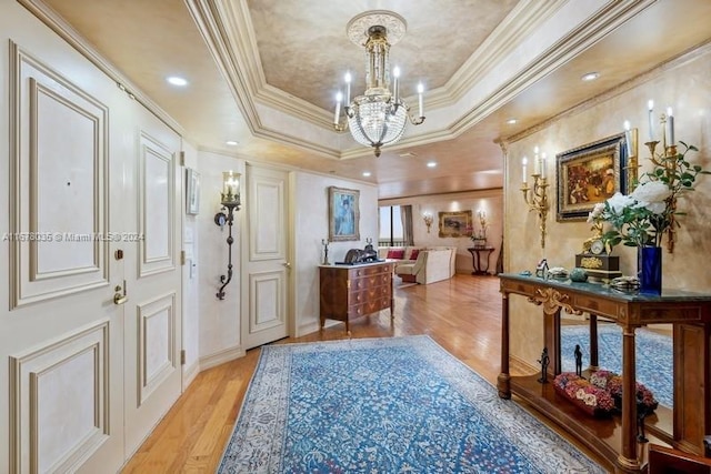 foyer featuring light hardwood / wood-style floors, crown molding, a chandelier, and a raised ceiling