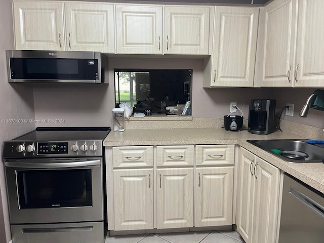 kitchen with stainless steel appliances, sink, and light tile patterned floors