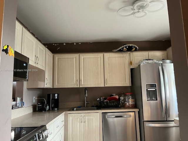 kitchen with stainless steel appliances, light brown cabinetry, and sink