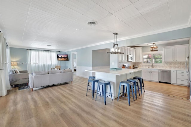 kitchen featuring appliances with stainless steel finishes, a kitchen bar, a center island, light hardwood / wood-style floors, and decorative light fixtures