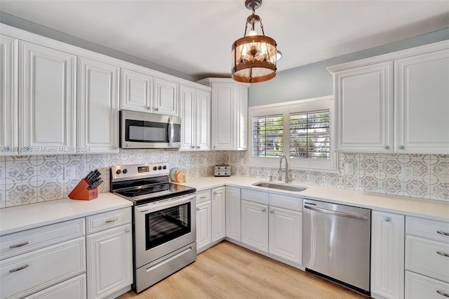 kitchen featuring decorative backsplash, stainless steel appliances, sink, white cabinets, and light hardwood / wood-style floors