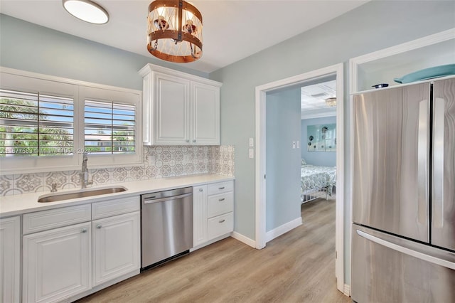 kitchen featuring stainless steel appliances, sink, white cabinetry, light hardwood / wood-style floors, and tasteful backsplash