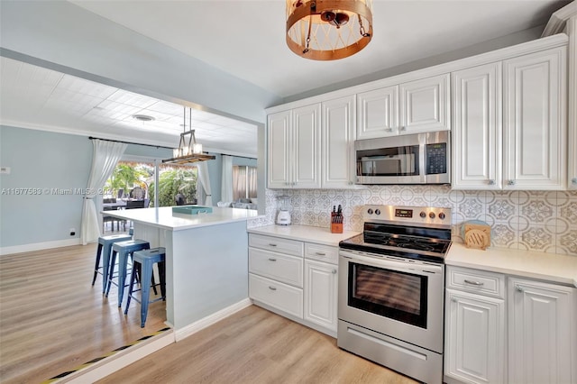 kitchen featuring pendant lighting, stainless steel appliances, kitchen peninsula, and white cabinets