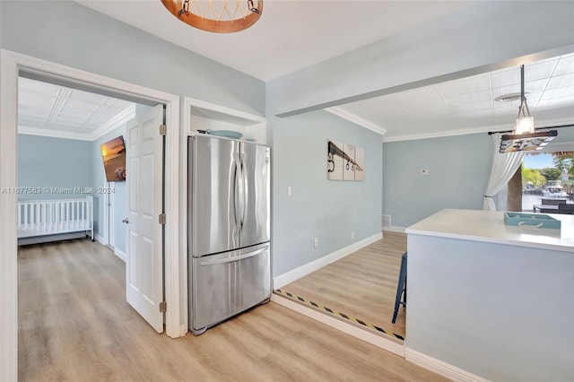 kitchen with crown molding, stainless steel refrigerator, decorative light fixtures, and light wood-type flooring