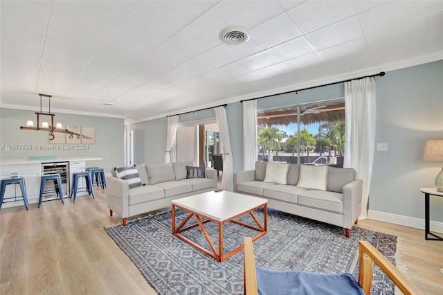 living room with ornamental molding, light hardwood / wood-style flooring, and a notable chandelier