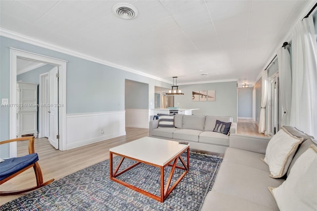 living room featuring ornamental molding, a chandelier, and light wood-type flooring