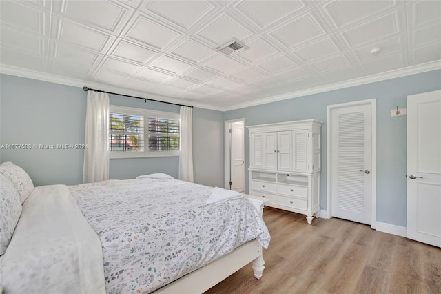 bedroom with ornamental molding and light hardwood / wood-style floors