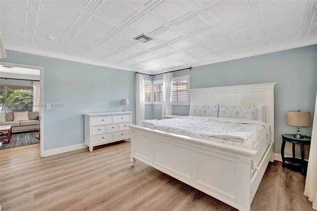 bedroom with ornamental molding and light wood-type flooring