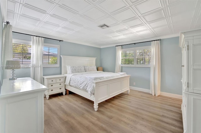 bedroom with ornamental molding and light hardwood / wood-style flooring