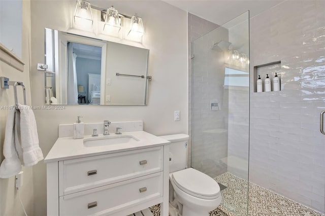 bathroom with vanity, toilet, and a tile shower