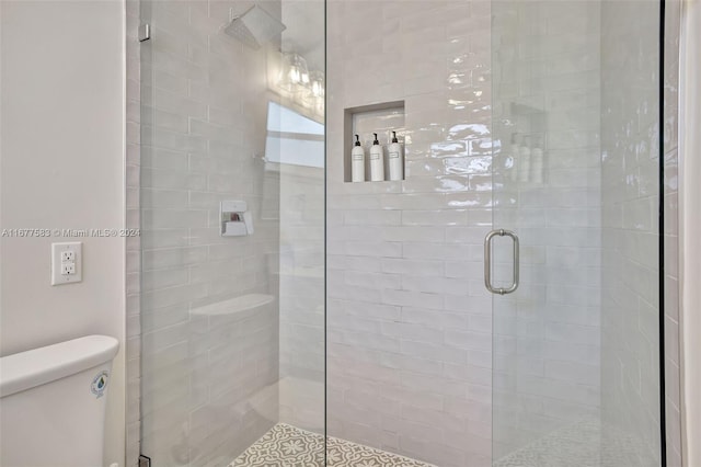 bathroom with a shower with door and toilet