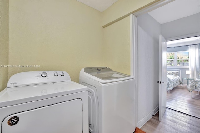 clothes washing area featuring light hardwood / wood-style flooring and washing machine and dryer