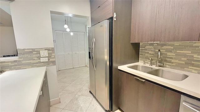 kitchen featuring decorative backsplash, hanging light fixtures, light tile patterned floors, appliances with stainless steel finishes, and sink