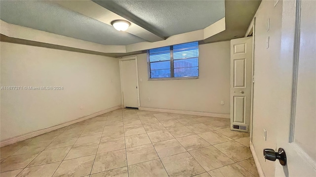 unfurnished room featuring a textured ceiling and light tile patterned flooring