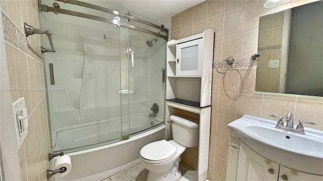 full bathroom with vanity, tile walls, bath / shower combo with glass door, and toilet