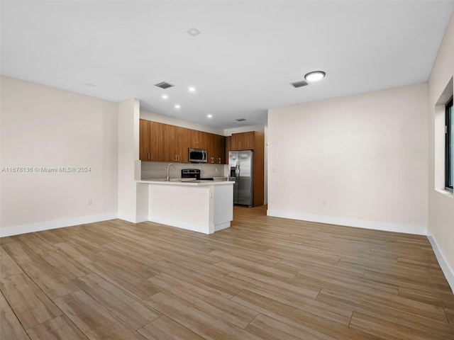 kitchen featuring light hardwood / wood-style floors, kitchen peninsula, sink, and appliances with stainless steel finishes