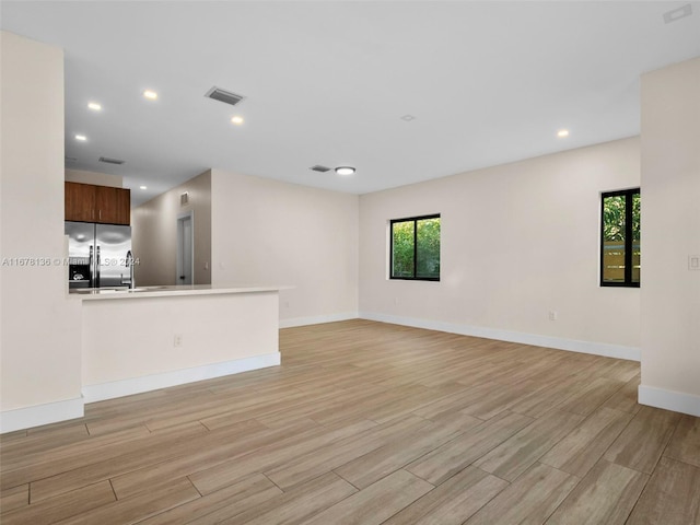 unfurnished living room with light hardwood / wood-style flooring and sink